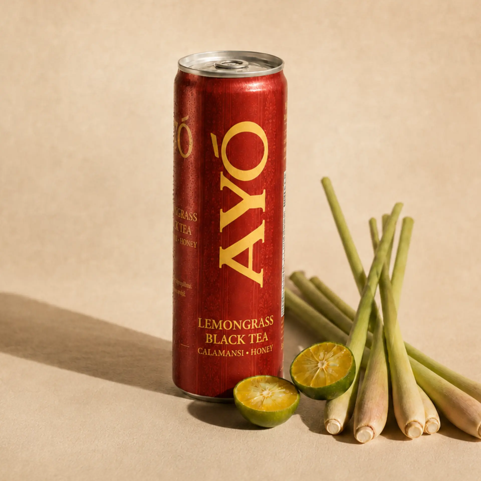 AYÓ Tanglad Black Tea can with lemongrass stalks and calamansi on a cream surface
